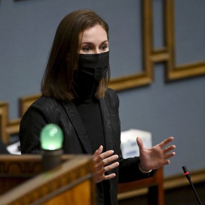 Sanna Marin med svart munskydd talar i riksdagen.