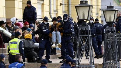 Polisen flyttar på en demonstrant utanför ett stenhus under en demonstration.