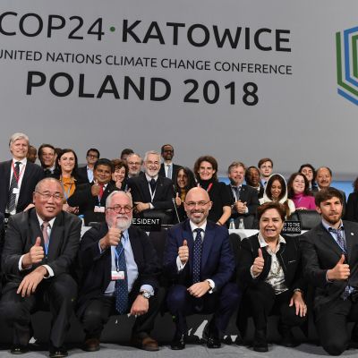 Medlemmarna på klimatkonferensen i Katowice visar upp glada miner efter att konferensen lidit mot sitt slut