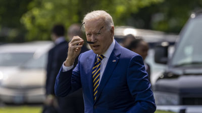 President Joe Biden sätter på sig solglasögon efter att han stigit ur en stor svart bild.