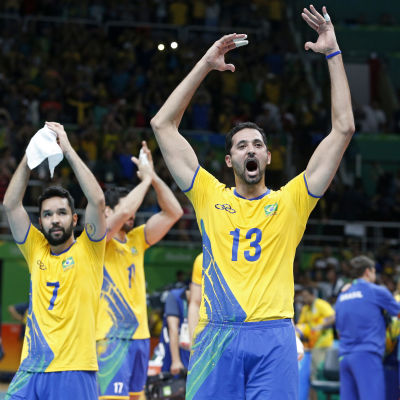 Två gulklädda brasilianska volleybollspelare jublar efter vinst.