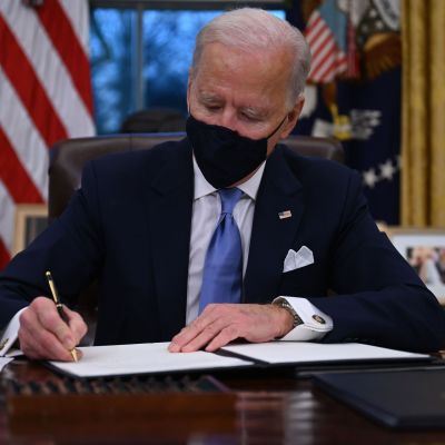 Joe Biden sitter i Ovala rummet i Vita huset och signerat presidentdekret.