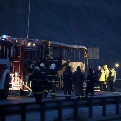 Brandmän och poliser står vid en brandbil efter en bussolycka i Bulgarien.