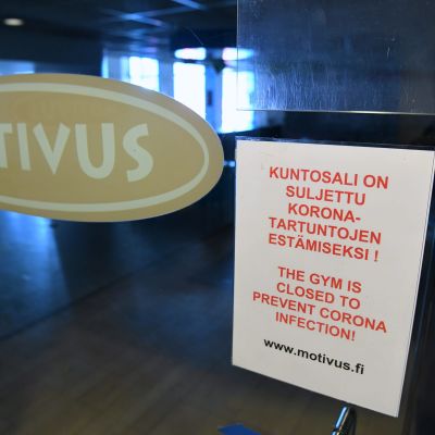 Motivus logo på en glasdörr. Bredvid en lapp om att gymmet är stängt.
