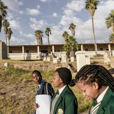 Skolflickor i Namibia Juni 2017. I bakgrunden ett monument till minne av dem som blev offer för det folkmord som Tyskland begick i början av 1900-talet.