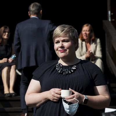 Annika Saarikko klädd i svart med en kaffekopp i handen.