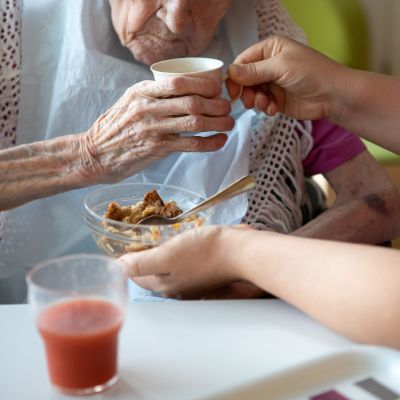 En vårdare hjälper en äldre klient att äta.