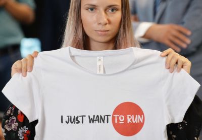 Kristina Tsimanovskaja under en presskonferens i Warszawa. Hon håller upp en t-skjorta med texten "I just want to run".