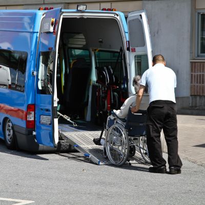En person i rullstol rullas in i en taxibil.
