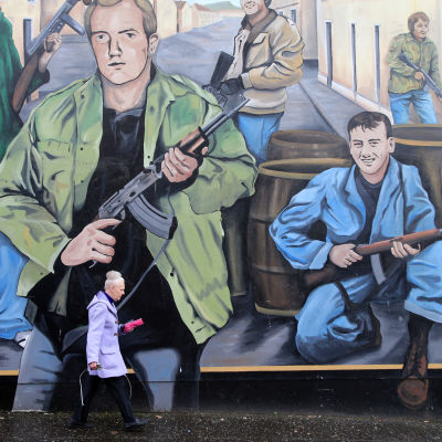 Kvinna framför en väggmålning i Nordirland.  