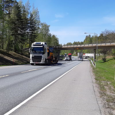 Långtradare och bilar kör på riksväg 25 i Ekenäs under en bro.