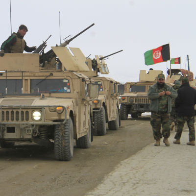 En konvoj med militärfordon, några män står intill bilarna.