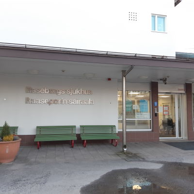 En bild på Raseborgs sjukhus byggnads entre. På väggen står raseborgs sjukhus med silvriga bokstäver