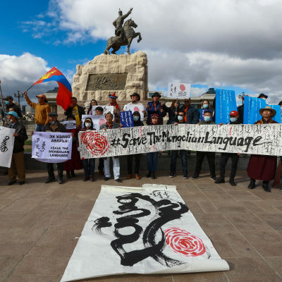 Demonstranter i Ulan Bator håller upp banderoller med texten "Rädda det mongoliska språket".