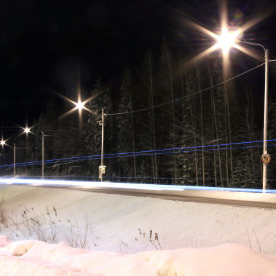 Gatulyktor som lyser över vintrig landsväg i mörker.