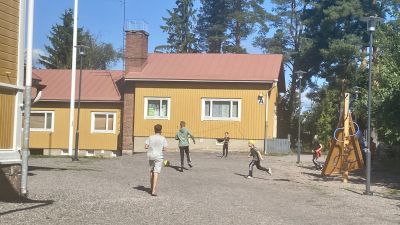 Elever spelar fotboll på en gårdsplan.