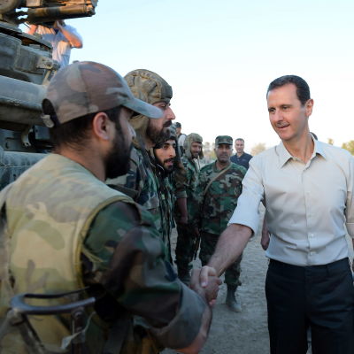 Bashar al-Assad skakar hand med en soldat.