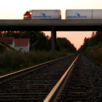 En långtradare susar förbi på en järnvägsbro.