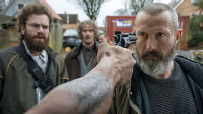 Markus (Mads Mikkelsen) står och stirrar på en man som siktar en pistol mot hans huvud.