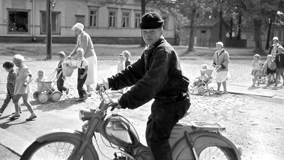 Foto av pojke på moped med barn i bakgrunden, på Karlskronabulevarden i Lovisa. Taget av Aatos Åkerblom