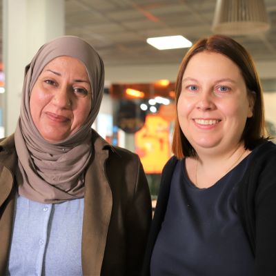 Irakista Suomeen tullut Roqaya Al-Anbagi ja suomalainen Paula Malan hymyilevät kameralle Trion kauppakeskuksessa Lahdessa.