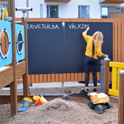 en kvinna står och skriver på en krittavla i en lekpark