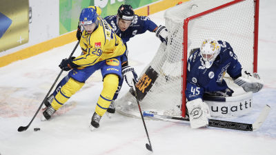 En finländsk och en svensk spelare rundar Jussi Olkinuoras mål.