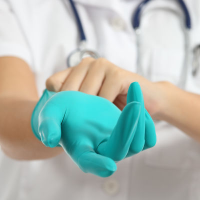En sjukskötare tar på sig plasthandskar.