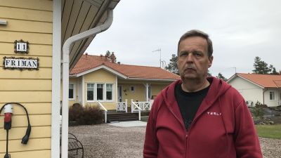 Rune Friman står med ett gult hus i bakgrunden