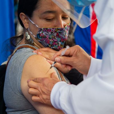 En kvinna i munskydd får coronavirusvaccin.