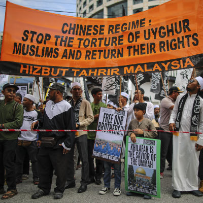 Personer demonstrerar mot Kinas behandling av den muslimska uigurbefolkningen.
