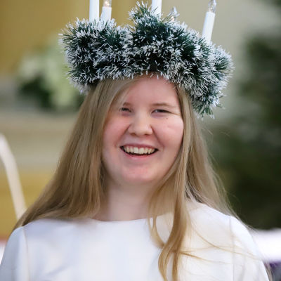 Mikkelin lukion Lucia-neito 2021 Mirella Snellman hymyilee hampaat näkyen kynttiläseppele päässään.