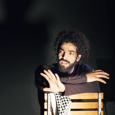 Ramy Essam sitter ner på en stol under föreställningen