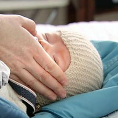 En hand smeker ett nyfött barns kind. 