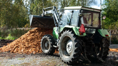 En traktor med lyftskopa hanterar pressrester av äpplen