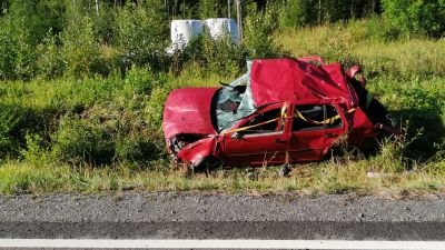 En röd personbil som varit med om en trafikolycka ligger i diket.