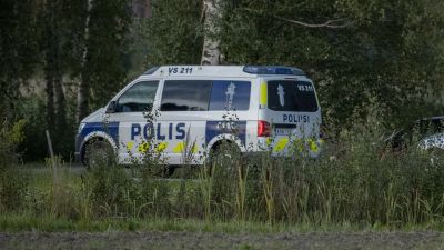 En polisbil vid en grusväg.