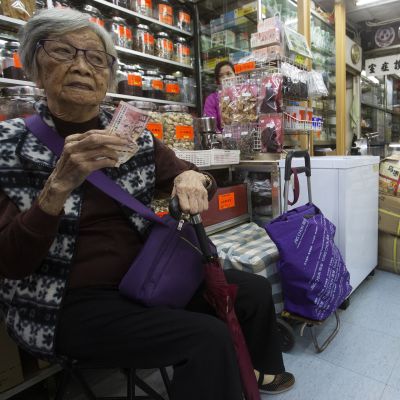En gråhårig kinesisk kvinna väntar i en apotek för traditionell kinesisk medicin