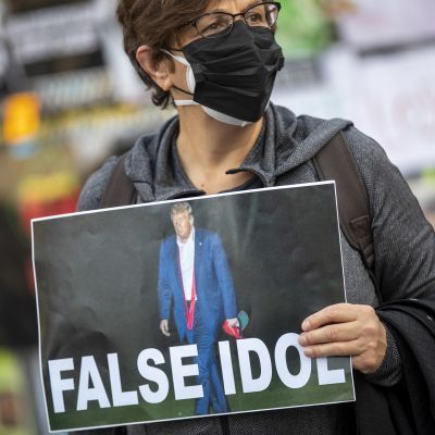 Nainen kantaa julistetta jossa lukee "False Idol"