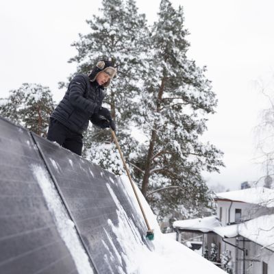 Espoolainen Ari Siipivirta pyyhkii lunta aurinkopaneelien päältä.