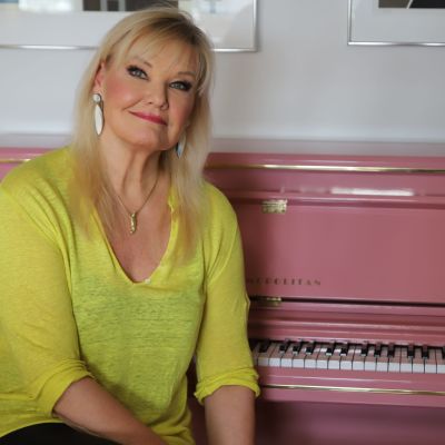 Karita Mattila sitter vid ett ljusrött piano.
