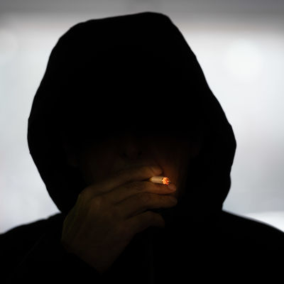 Anonyymi hupparimies polttaa tupakkaa.