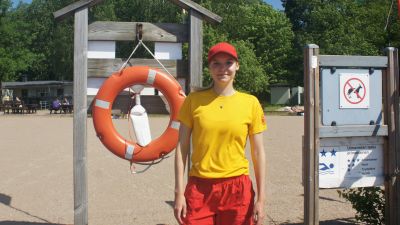Badvakten Alexandra Pihlajamäki bredvid en livboj på Ekvalla badstrand.