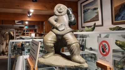 Tälstensfigur på ett glaspodium.