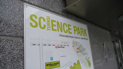 Närbild av Science Parks grönvita skylt på husväggen.