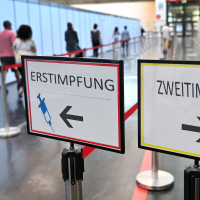 Två tyskspråkiga skyltar som dirigerar till två olika köer beroende på om man är vaccinerad eller ej.