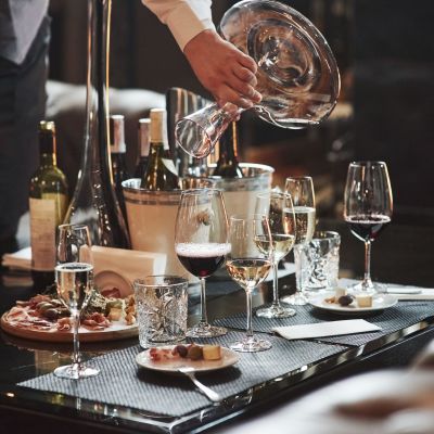 En servitör häller vin på en restaurang. På bordet står vinglas och mat.