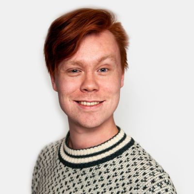 Alexander Beijar ser in i kameran och ler, med en vit ylletröja på sig och en vit bakgrund.