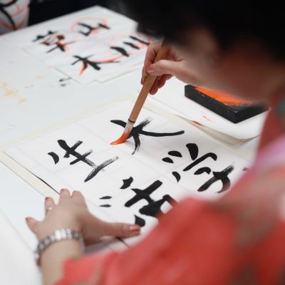 Henkilö kirjoittaa siveltimellä japanilaista kalligrafiaa.