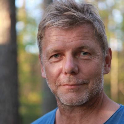 Mieshenkilö sinisessä paidassa hymyilee ja katsoo kameraan.